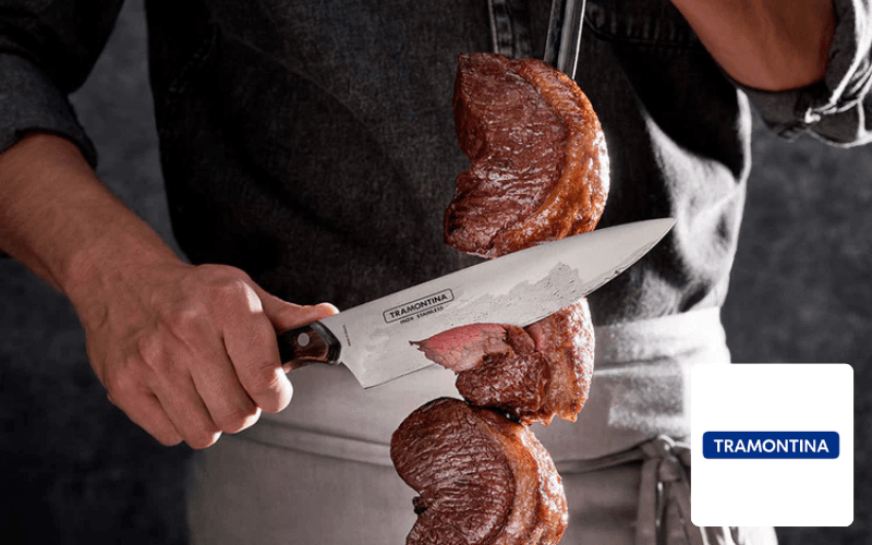 Person schneidet gegrilltes Fleisch mit einem Tramontina Messer vom Spieß